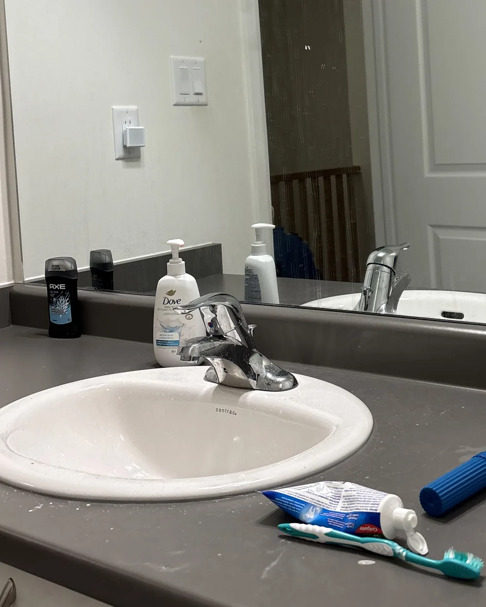 A bathroom sink and counter with items left out and marks on the surface