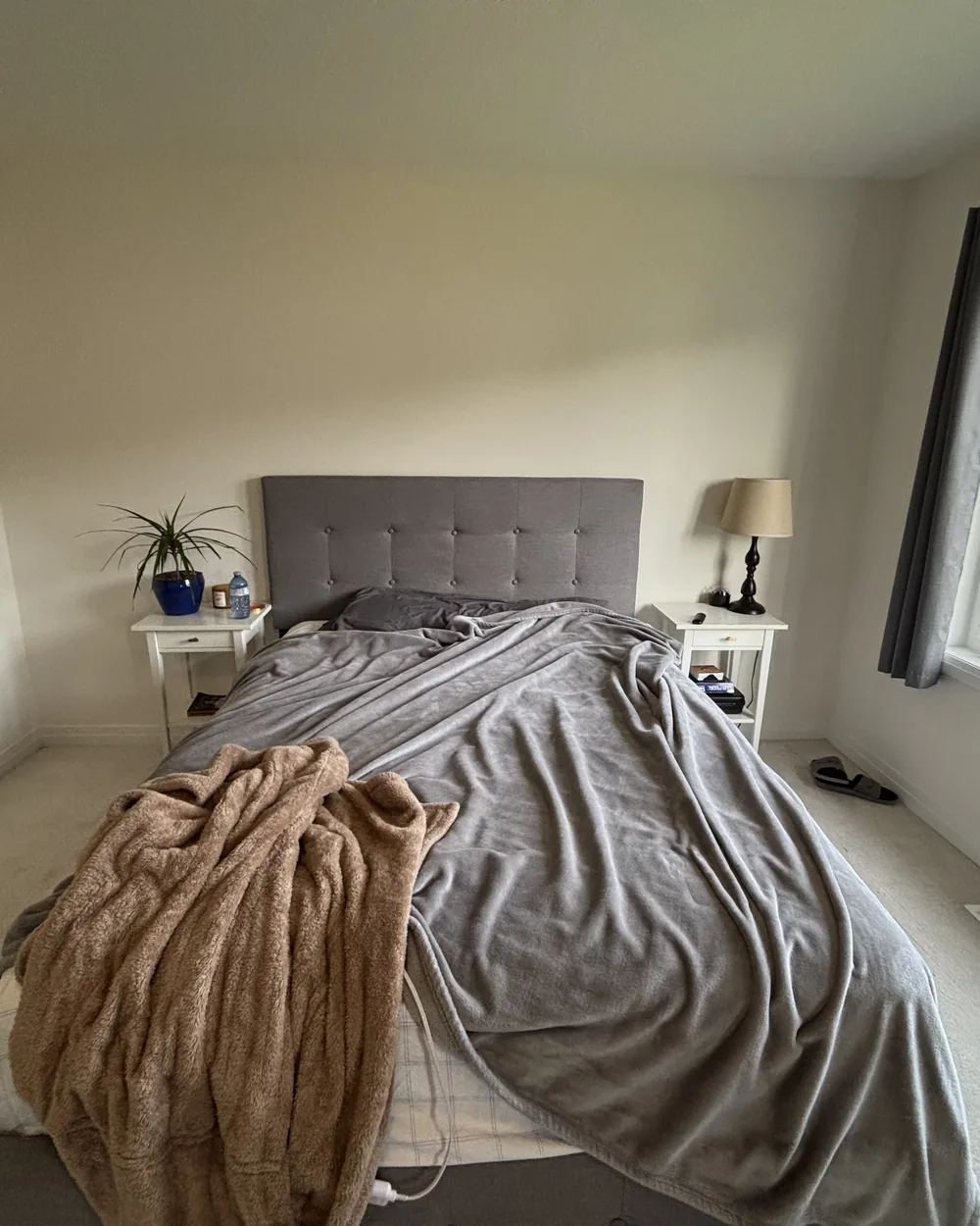 A bedroom with the bed unmade and throws piled on top
