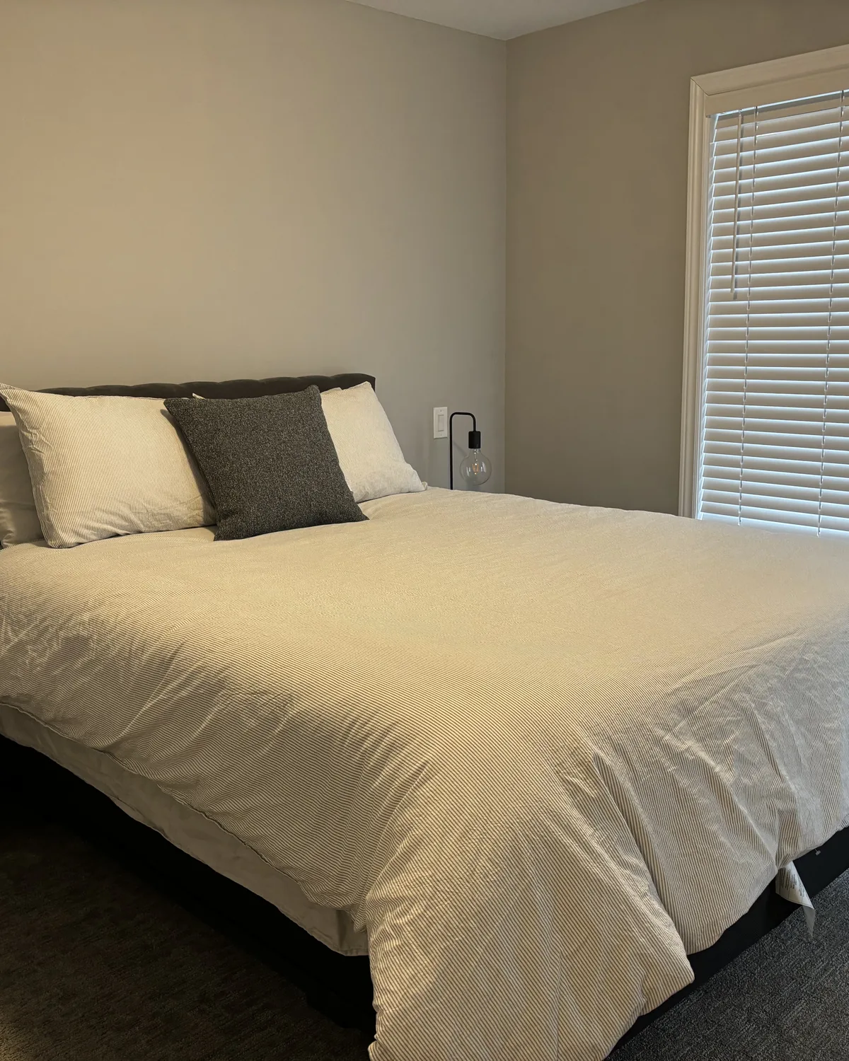 A neatly made bed with white bedding in a bright bedroom